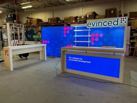 Custom 10 ft./20 ft. Inline Exhibit with Double-sided Lightbox, Halo Lit Logo, Custom Counter with Storage, Genius Bar with Electrical Outlets, and Shelves. Re-configurable Design